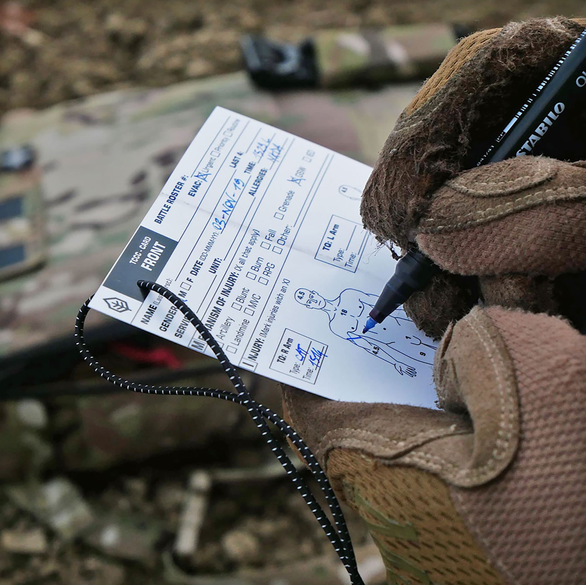 Paper TCCC casualty card being filled out in the field